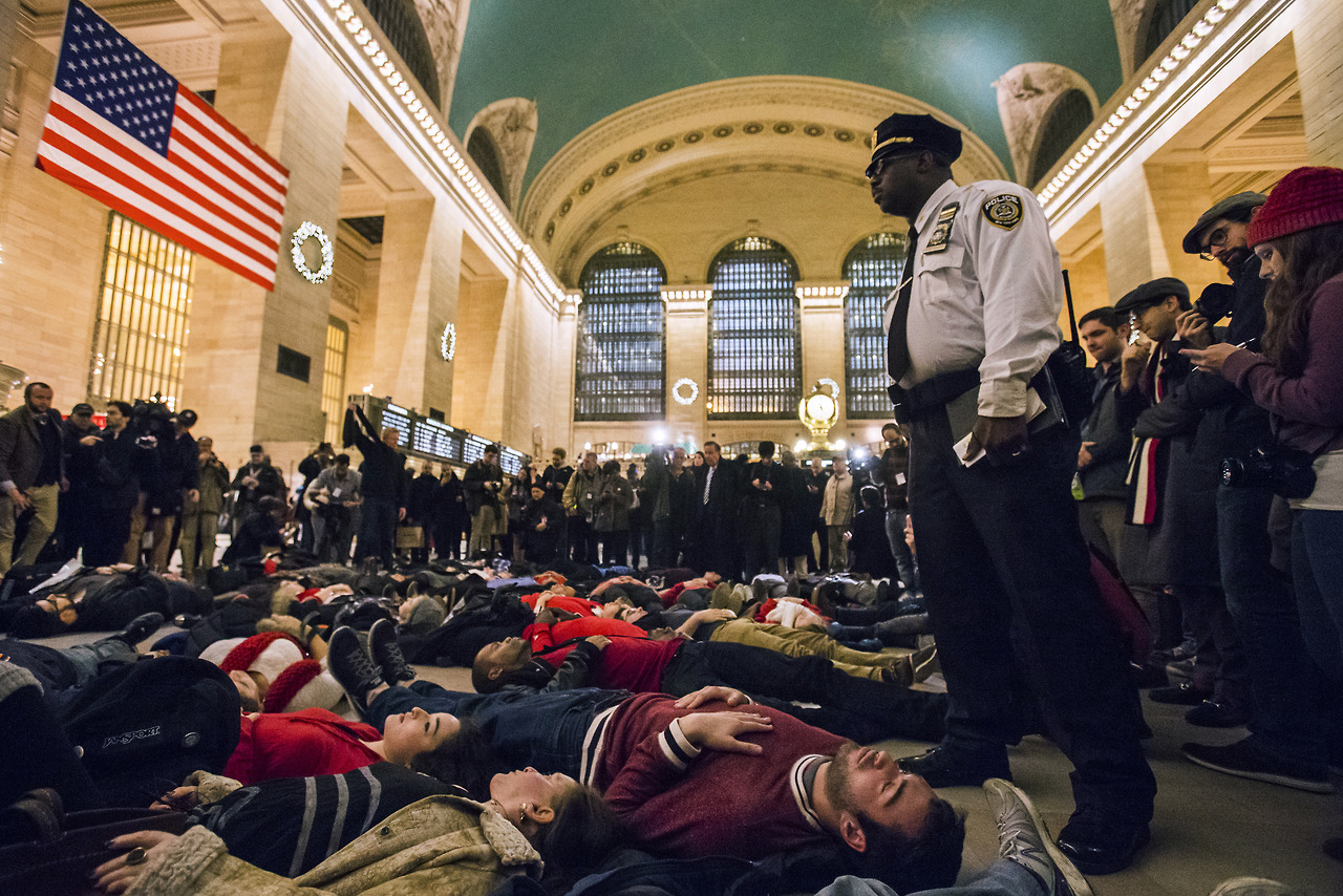 A police officer stands over activists, demanding justice for the death of Eric Garner, as they stage a 'die-in' during rush hour at Grand Central Terminal in the Manhattan borough of New York